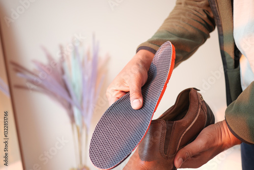 Foto Person placing new insole into brown leather shoe at home