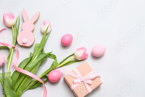 Easter eggs with gift box, toy rabbit and beautiful tulip flowers on grey background
