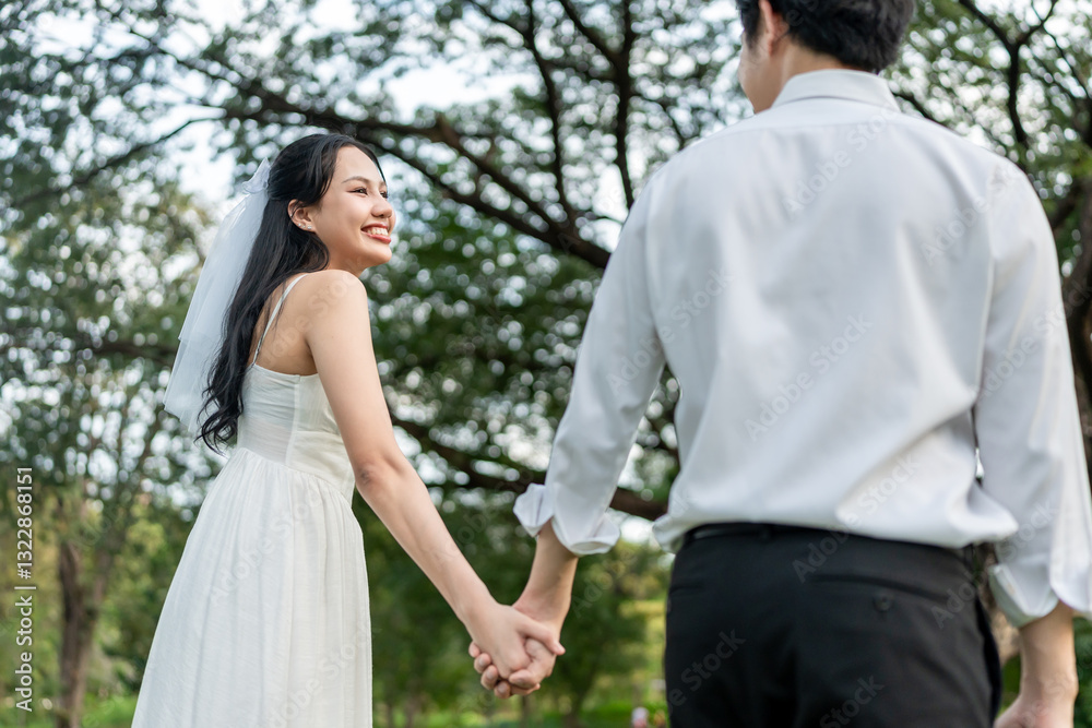 Asian young married couple holding hand each other in park during sunset. Asian young married couple holding hand each other in park during sunset.