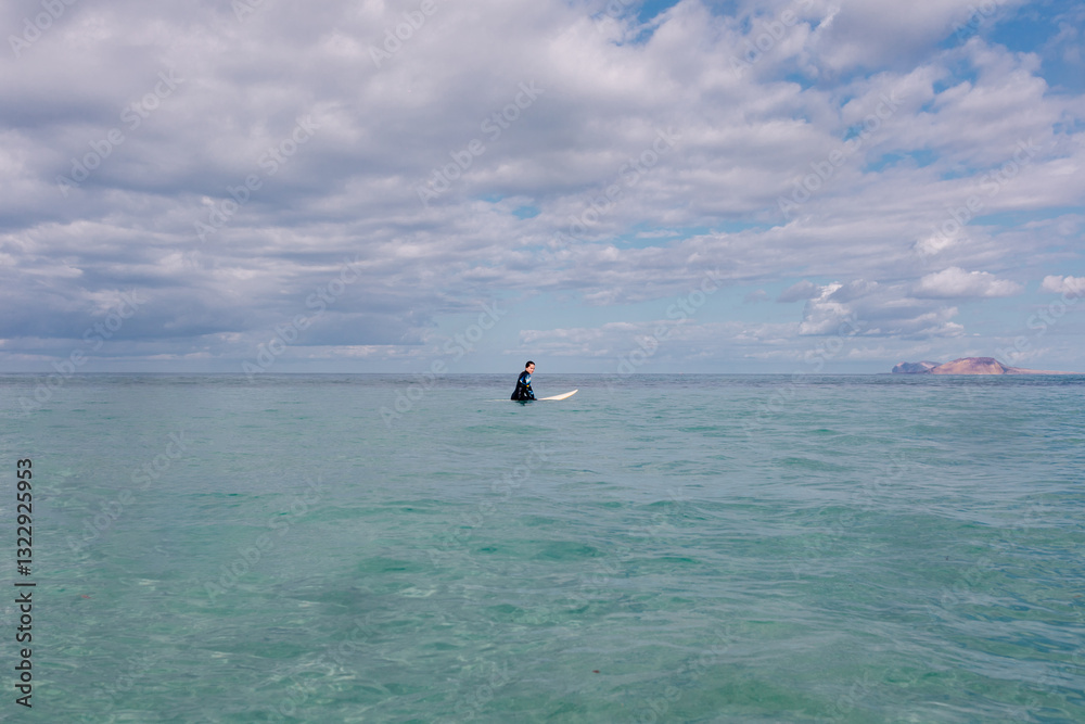 Panoramic shot of a surfer floating in the middle of a vast seascape Panoramic shot of a surfer floating in the middle of a vast seascape