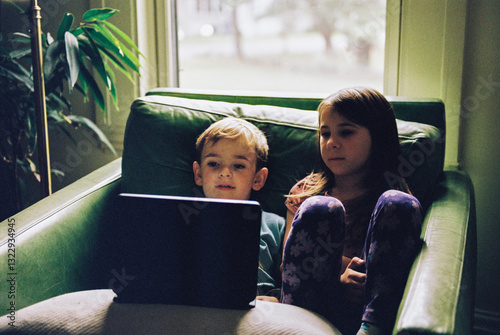 Siblings stream a show together on a tablet at home photo