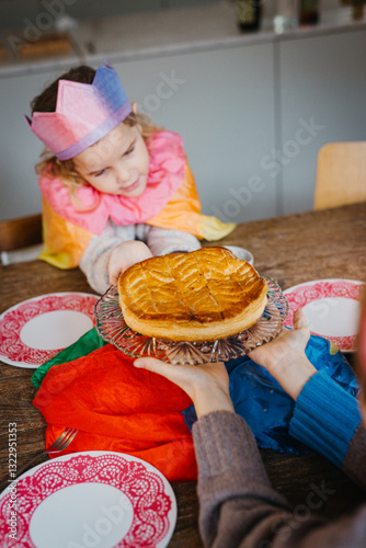 young girl in colorful attire reaching for a pie on table. photo