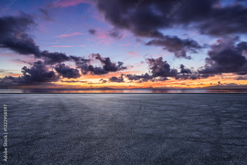 Empty asphalt road with dramatic sunset sky and ocean view