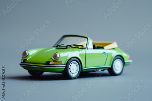 A small green convertible automobile sits on a plain gray backdrop