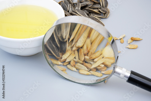 Fotografie Close up of sunflower seeds under magnifying glass and oil in bowl