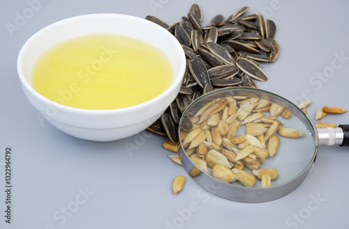 Fotografie Sunflower seeds under magnifying glass and oil in bowl on gray background