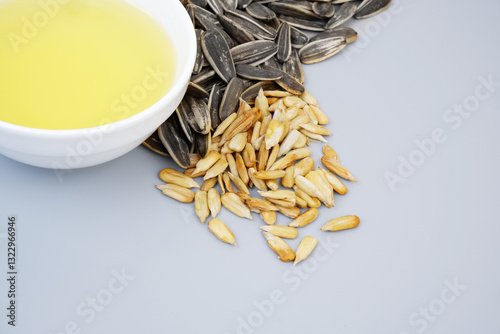 Sunflower seeds and oil in bowl on gray background, copy space for text.