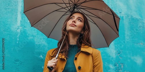 A woman is holding an umbrella and looking up at the sky