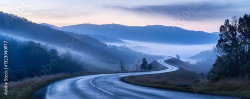 A winding road passes through misty mountains at dawn