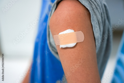 Close-up photograph of a bandage and gauze covering a boy's upper arm after receiving a flu shot at a hospital.