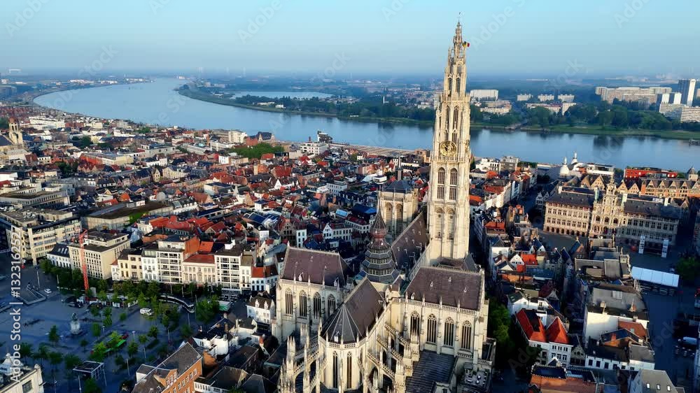 Summer Morning in Antwerp Aerial View of the Cathedral of Our Lady, Its Towering Spire Dominating the Historic Cityscape, with the River Scheldt Curving in the Background, Under a Clear Softly Lit Sky