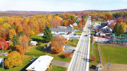 Two cars driving on the national highway and passing through a small town in Estrie with the trees colored with the Autumn colors