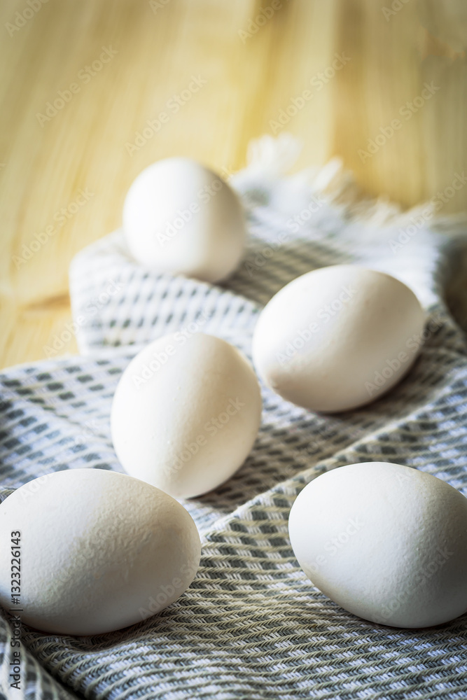 White eggs scattered on a textured linen napkin on a wooden table. Soft natural light enhances the organic and rustic feel, making it a perfect image for Easter, farm-fresh food, and cooking themes White eggs scattered on a textured linen napkin on a wooden table. Soft natural light enhances the organic and rustic feel, making it a perfect image for Easter, farm-fresh food, and cooking themes