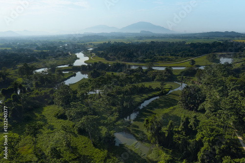 Stunning aerial view of a winding river surrounded by lush greenery, rolling hills, and distant mountains, capturing the beauty of nature