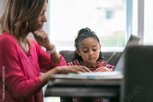 Home: Little Girl Doing Math Homework While Mother Works Remotel photo