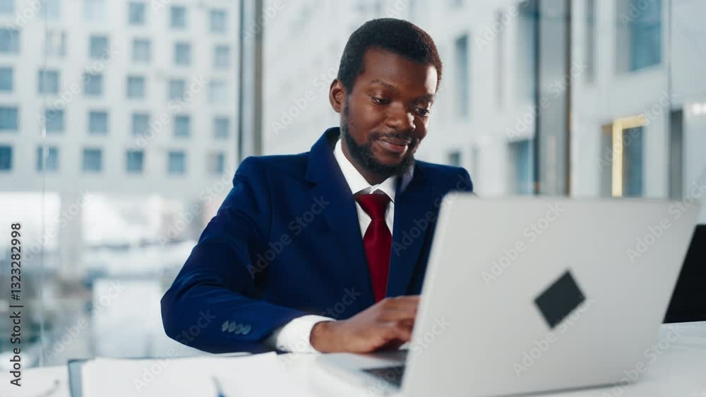 Successful investor sitting alone in office, working with laptop, portrait. Rich black man in expensive business suit making notes on paper when looking at display, management and strategic planning Successful investor sitting alone in office, working with laptop, portrait. Rich black man in expensive business suit making notes on paper when looking at display, management and strategic planning