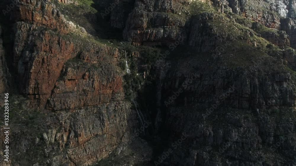 Flight approaches small waterfall on massive rugged rock canyon cliff Flight approaches small waterfall on massive rugged rock canyon cliff