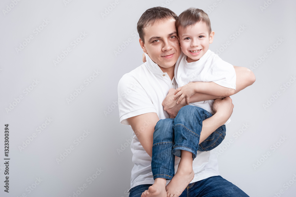 Family Values Concepts. Portrait of Caucasian Father with Son Wearing White Shirts Posing in Studio Against White Background. Family Values Concepts. Portrait of Caucasian Father with Son Wearing White Shirts Posing in Studio Against White Background.