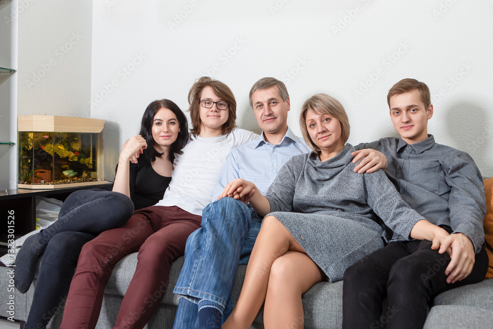 Family Concepts. Happy Caucasian Family Get Together Embracing and Sitting on Sofa Indoors With Positive Expression Family Concepts. Happy Caucasian Family Get Together Embracing and Sitting on Sofa Indoors With Positive Expression