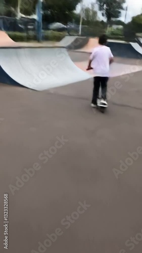 Wallpaper Mural A boy rides a scooter in a skate park, gliding over ramps and performing tricks, with an urban backdrop capturing the energy of extreme sports. Generative AI Torontodigital.ca