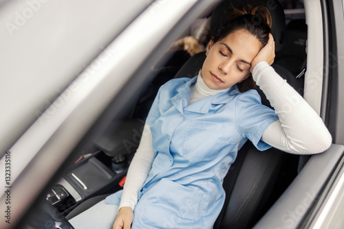 Exhausted female doctor sleeping in her car after night shift in hospital.
