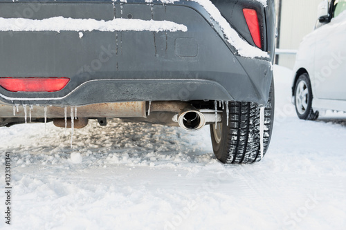 Close-up of a car exhaust pipe with icicles and snow