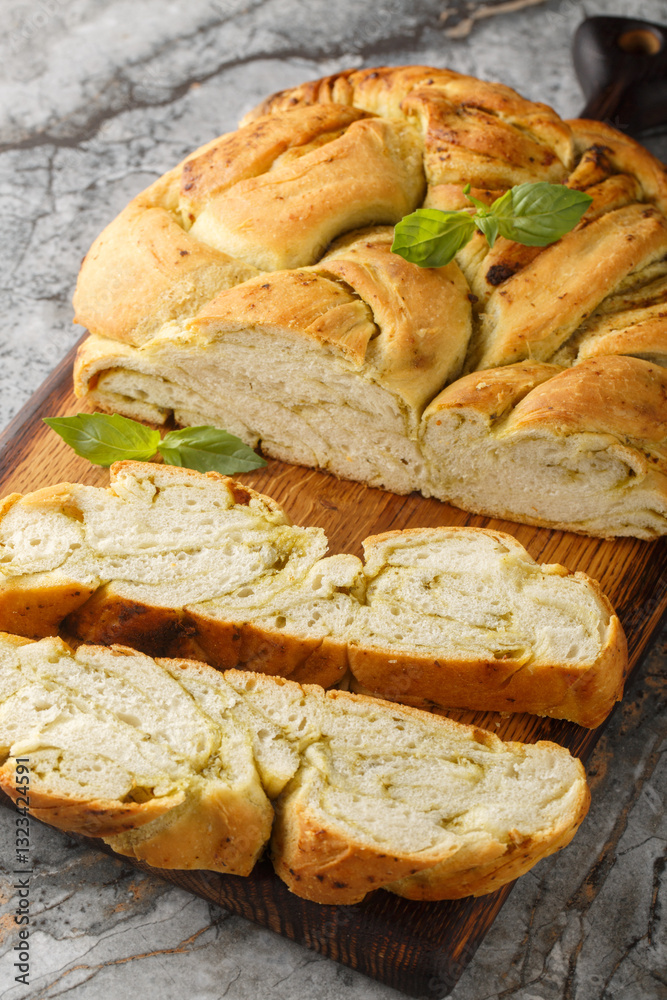 Homemade bread is braided with basil pesto closeup on the wooden board on the table. Vertical