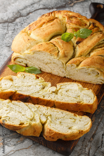 Obraz na płótnie Homemade bread is braided with basil pesto closeup on the wooden board on the table. Vertical w salonie