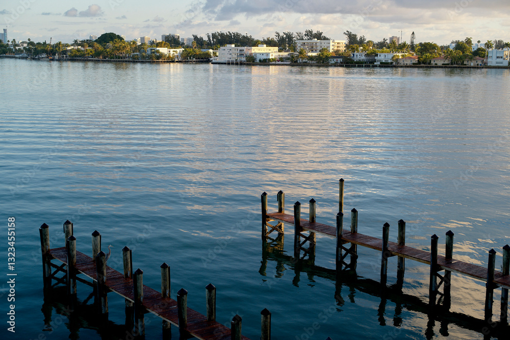 Wooden piers extend over calm waters with a distant view of a tree-lined shore. Miami, FL, USA Wooden piers extend over calm waters with a distant view of a tree-lined shore. Miami, FL, USA