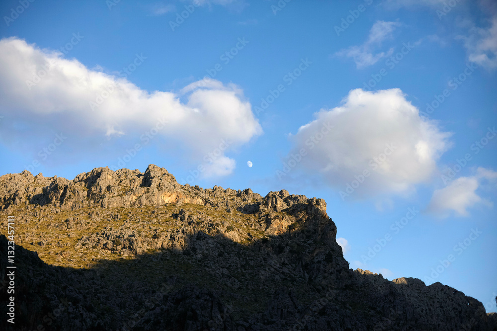 Rocky mountain peak with clouds and clear blue sky during daytime. Mallorca, Spain Rocky mountain peak with clouds and clear blue sky during daytime. Mallorca, Spain