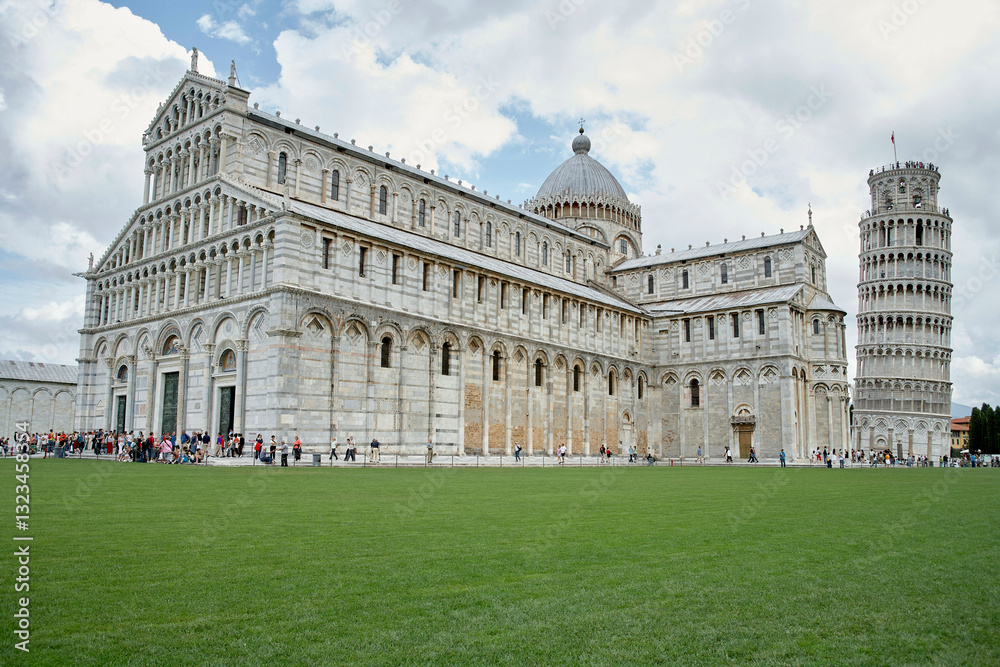 Leaning Tower of Pisa and Pisa Cathedral under a cloudy blue sky with green grass in front. Leaning Tower of Pisa and Pisa Cathedral under a cloudy blue sky with green grass in front.