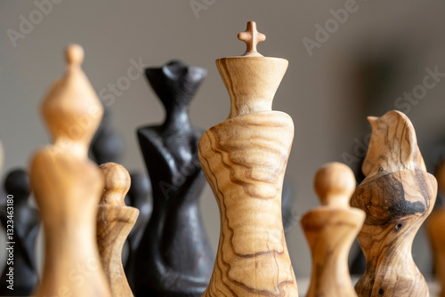 Artistic wooden chess pieces on a board, focusing on the king in soft natural lighting. Nijmegen, Netherlands