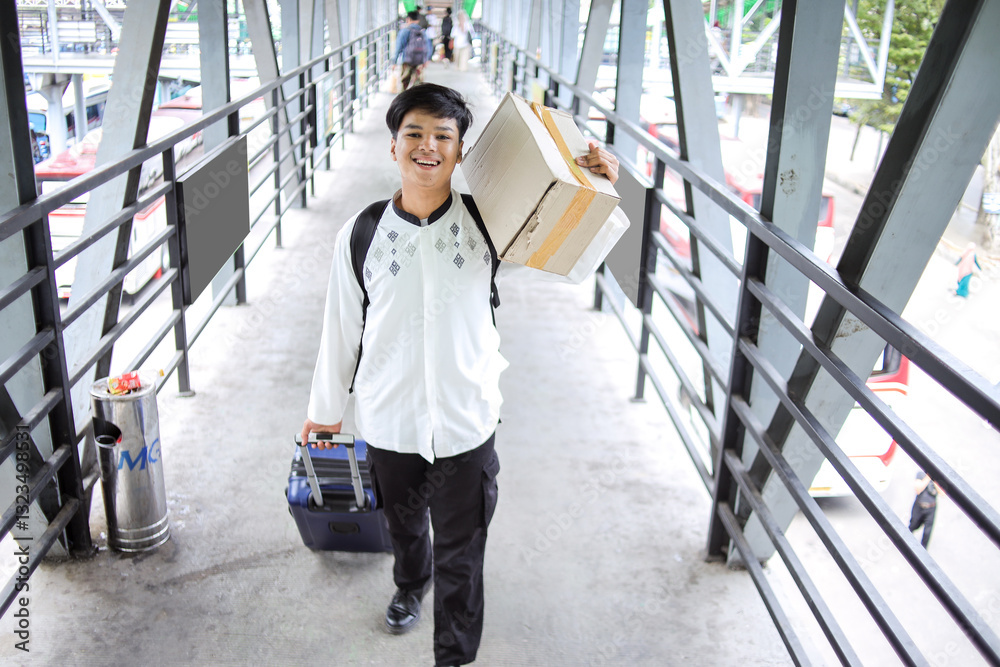 Male Muslim Walking While Pulling Suitcase and Carrying Package at Airport Terminal. Homecoming for Eid Al Fitr. Male Muslim Walking While Pulling Suitcase and Carrying Package at Airport Terminal. Homecoming for Eid Al Fitr.