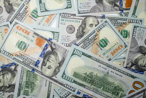 Stacks of hundred dollar bills spread out on a surface highlighting the details of the new currency design