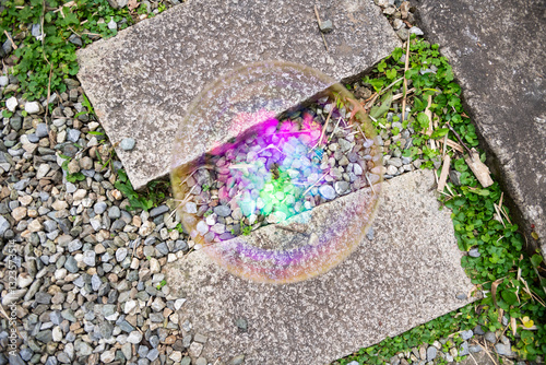 Iridescent Bubble on Pebbles and Concrete in an Outdoor Setting photo