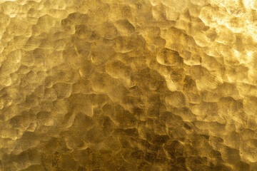 Abstract background of golden hammered brass surface. Metallic texture or pattern for backdrop design.