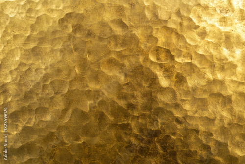 Abstract background of golden hammered brass surface. Metallic texture or pattern for backdrop design.