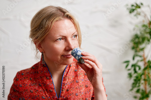 Принти на полотні Woman in ceremonial attire enjoying tea moment with traditional setup, reflectin