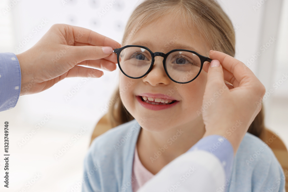 Vision testing. Ophthalmologist giving glasses to little girl indoors, closeup Vision testing. Ophthalmologist giving glasses to little girl indoors, closeup