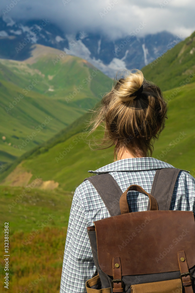 Female hiker with backpack enjoying stunning view of snow-capped mountains and green valleys in the svaneti region of georgia, showcasing the beauty of nature and the spirit of adventure