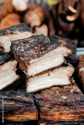 Butcher selling tasty homemade bacon on fair, farmers market stand.