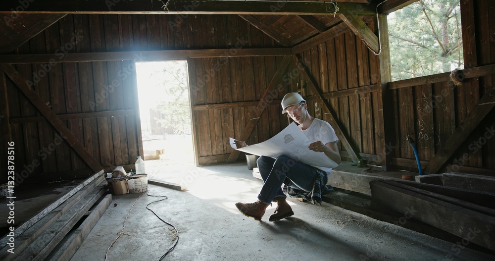 A Focused Worker Diligently Analyzing Detailed Plans Within a Rustic Barn Environment