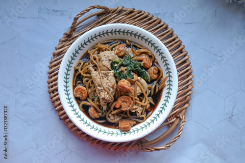 A  bowl of Mee Hailam, with tender noodles, shrimp, chicken, vegetables, and a rich, aromatic broth.