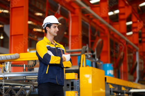 Wallpaper Mural Hispanic man worker in safety hardhat helmet at steel factory, metal sheets and industrial machinery in a large manufacturing plant. Torontodigital.ca