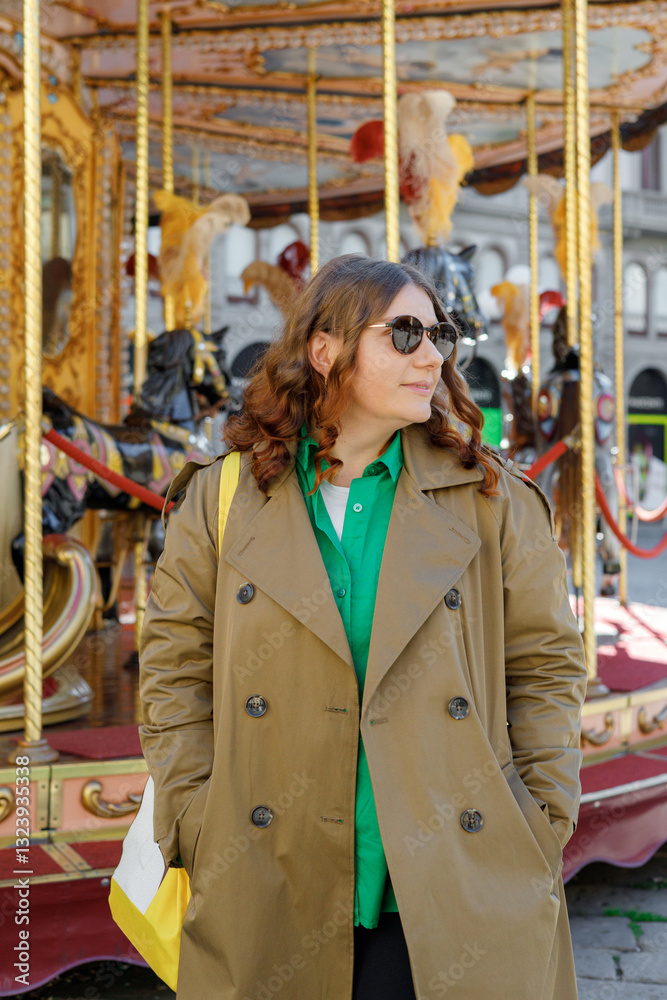 Cheerful young pretty woman in sunglasses with brown hair walking in park of attractions, wearing casual clothes