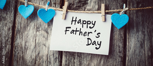 A heartfelt Father’s Day card pinned to a rustic wooden background with decorative blue hearts symbolizing love and appreciation  
