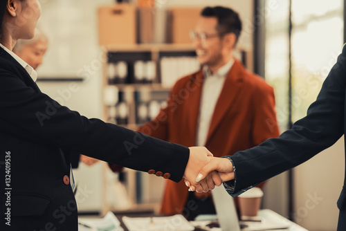A group of young business people are meeting, shaking hands and introducing themselves in the office. Business partners from different countries greet each other.