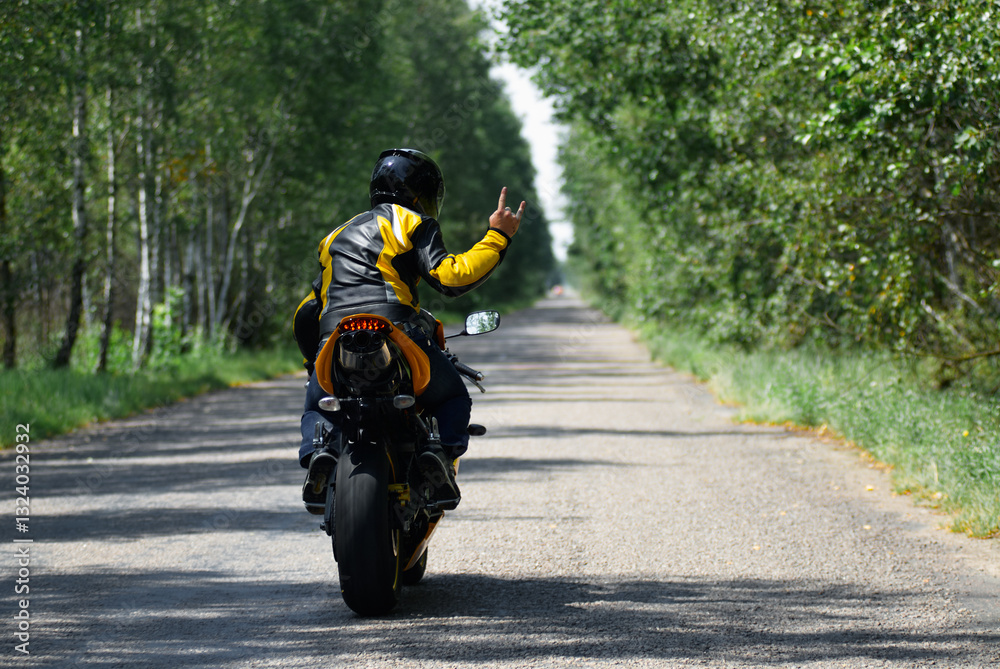 Motorcyclist Riding Along a Scenic Forest Road on a Sunny Day.. Motorcyclist Riding Along a Scenic Forest Road on a Sunny Day..