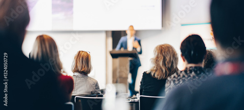 Speaker giving a talk in conference hall at business event. Rear view of unrecognizable people in audience at the conference hall. Business and entrepreneurship concept