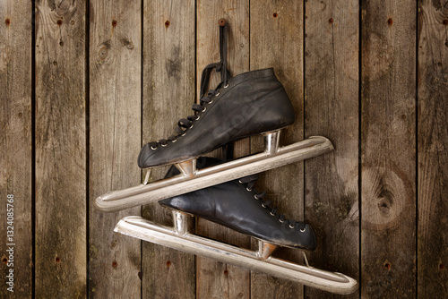 Black old skates hanging from laces on a wooden wall